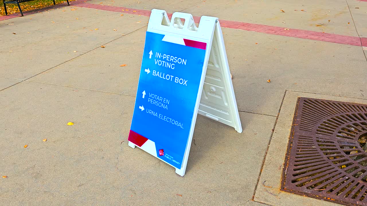 A bold ballot box sign with arrows highlights in-person voting, guiding citizens to the polls, featuring Spanish words Votar en Persona and Urna Electoral to symbolize inclusivity, trust and democracy