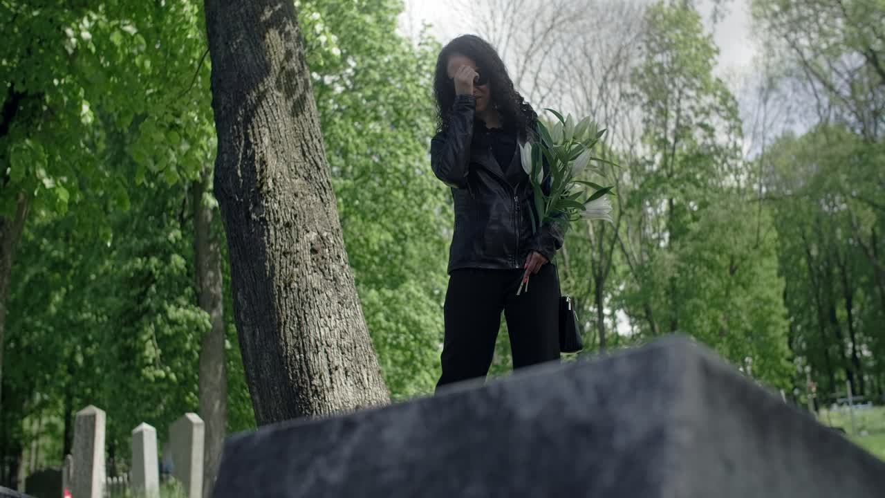 Woman in Grief at Cemetery with Flowers