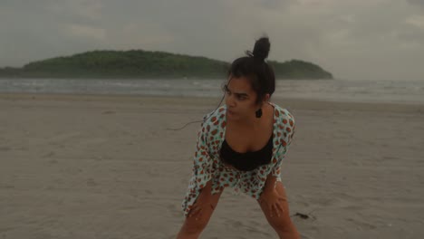 disparo central de una mujer india practicando yoga en la pintoresca playa