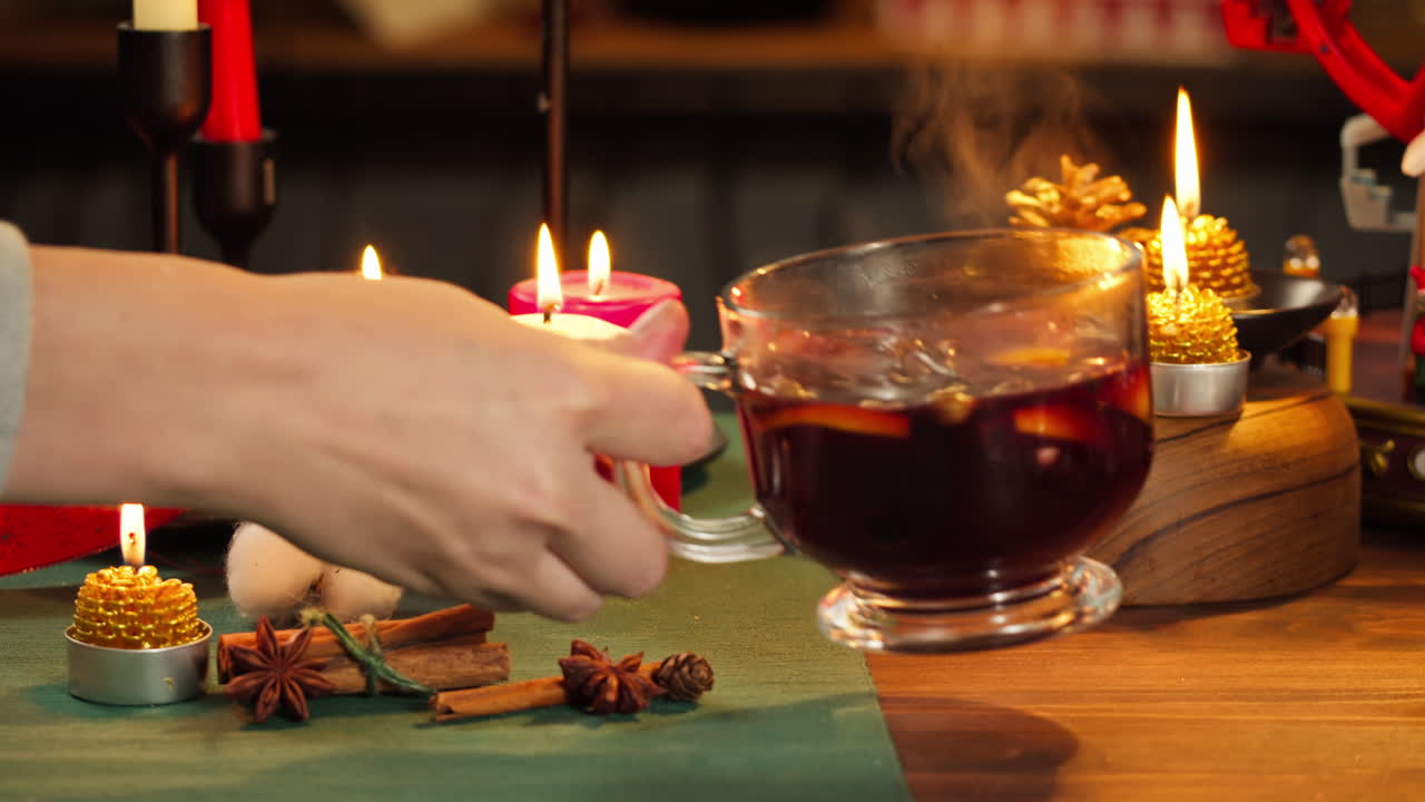 Warmer Glühwein mit Gewürzen und Kerzen auf einem festlichen Tisch