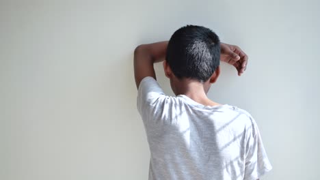 un niño apoyado en una pared.