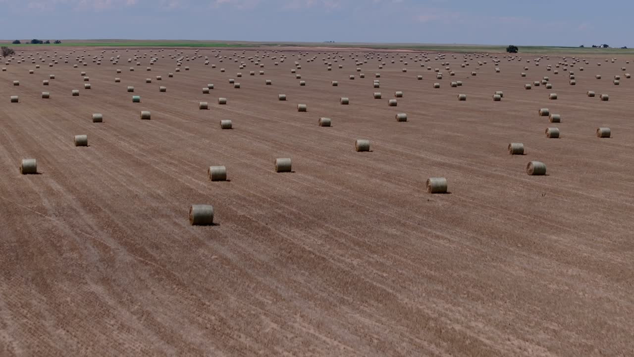 Drone aerial showing hay bales stretching across vast, open Kansas farmland