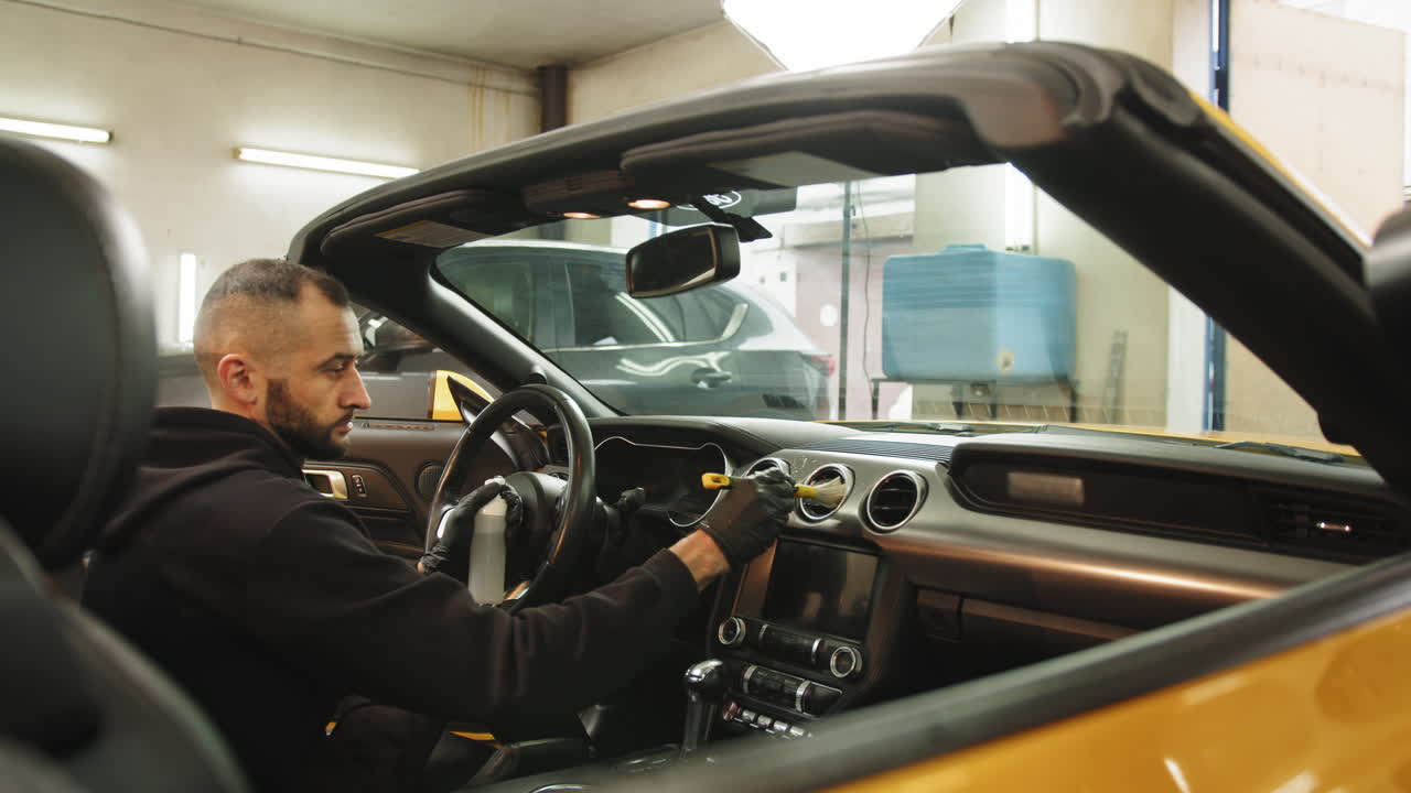 detallista de automóviles limpiando el interior de un descapotable amarillo