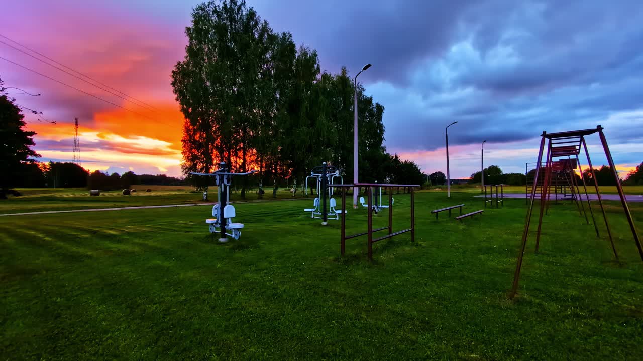 Outdoor gym and fitness equipment in park field under sunset evening sky