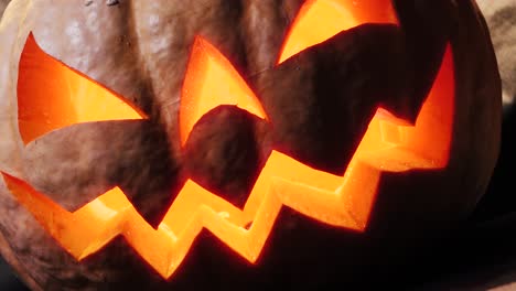 halloween pumpkin with a scary face and a spider on the eye, illuminated from the inside multicolored lights, a very scary pumpkin for halloween