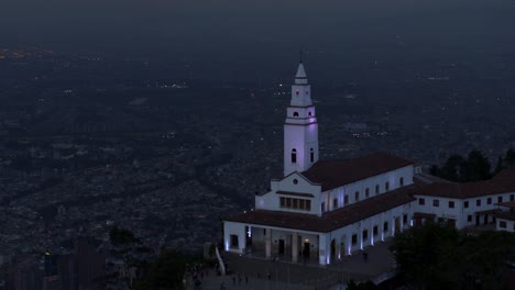 tomada de avión no tripulado de la iglesia de monserrate con vistas a la ciudad de bogotá, colombia en la hora azul