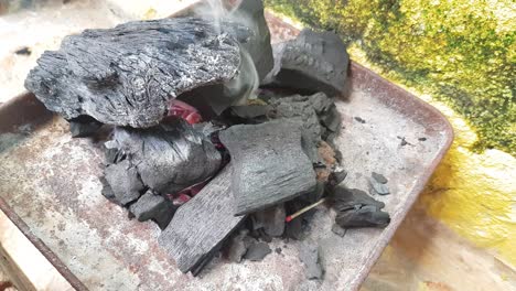 close up to a pile of coal burning on a metal can to prepare food