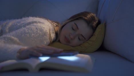 chica joven durmiendo en el sofá por la noche mirando el teléfono.
