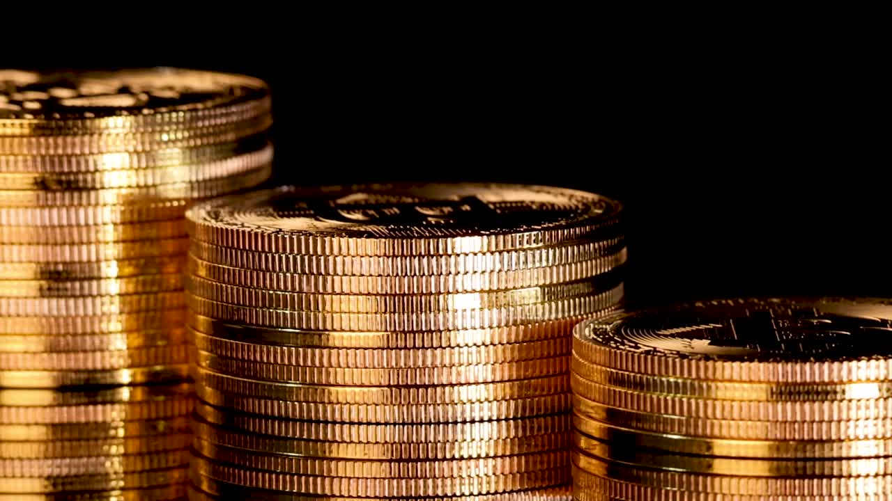 Macro view of shiny gold coin stacks spinning with dramatic lighting and reflections