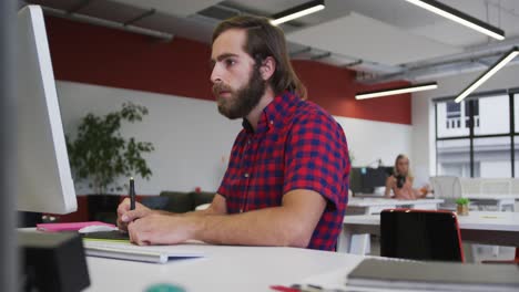 caucasian businessman using a computer going through paperwork in modern office