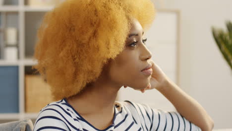 Close-Up-Of-The-Attractive-Woman-With-Curly-Short-Hair-Turning-Her-Head-To-The-Camera-And-Smiling-Sincerely-In-The-Light-Room