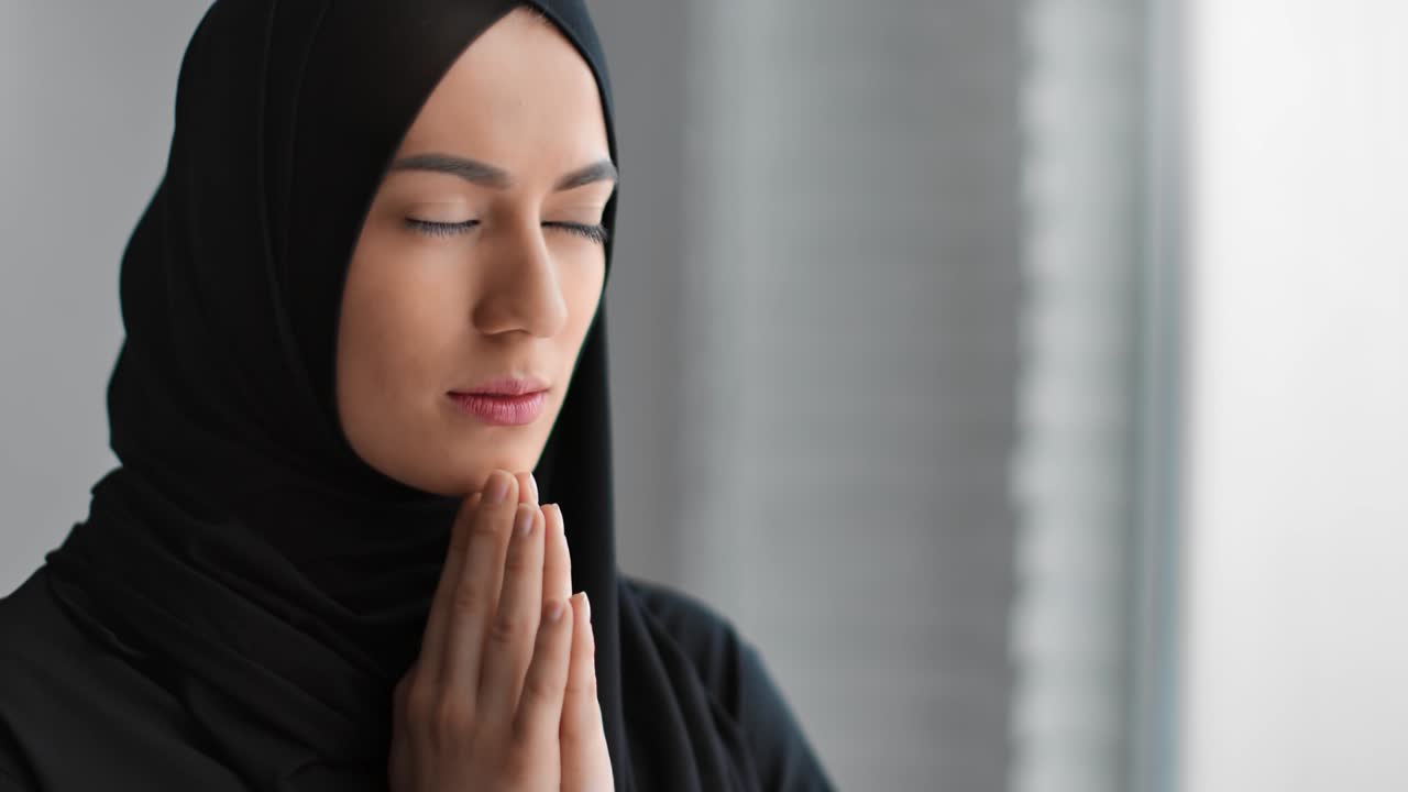 Donna araba tradizionale che prega con le mani unite, sognando e chiedendo ad Allah. Ripreso con telecamera RED in 4K.