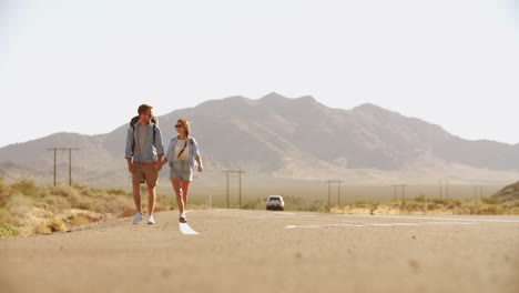 couple on vacation hitchhiking along road shot on r3d