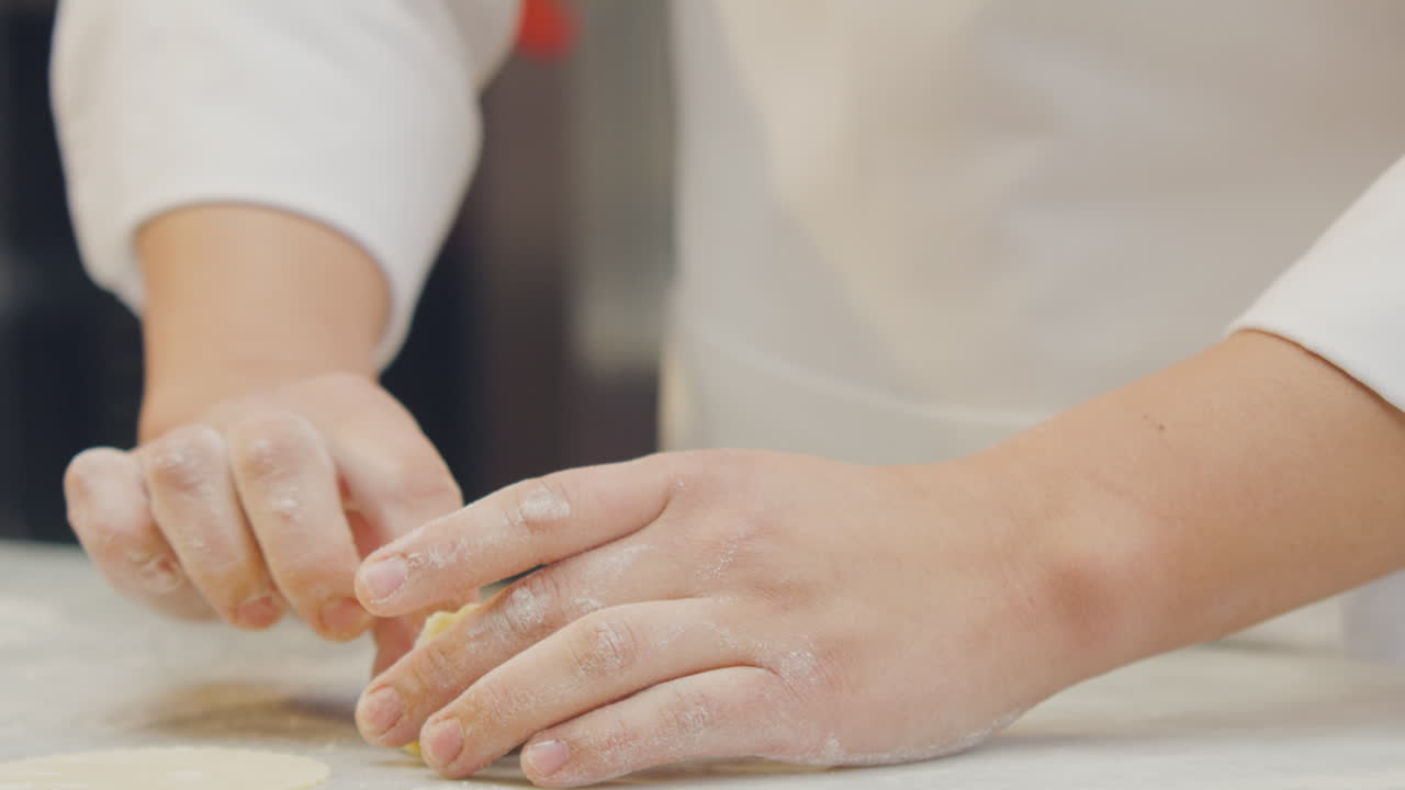 Chef's hands shaping, cutting the dough and filling the Ravioli with artisanal technique in a professional kitchen