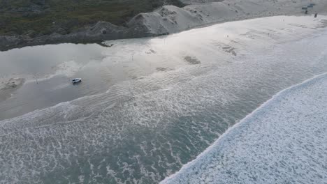 aerial drone shot of truck driving on pismo beach california through water at sunrise