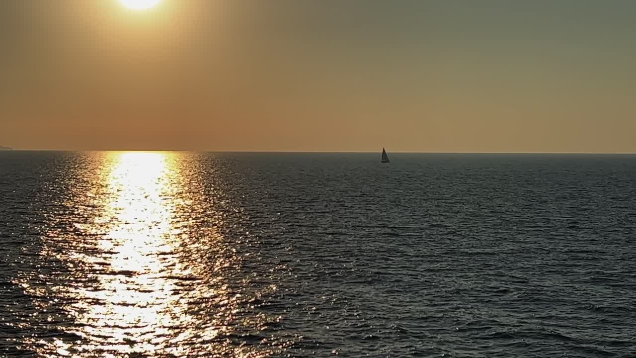 해가 지는 동안 열린 바다에서 멀리 항해하는 항해 보트