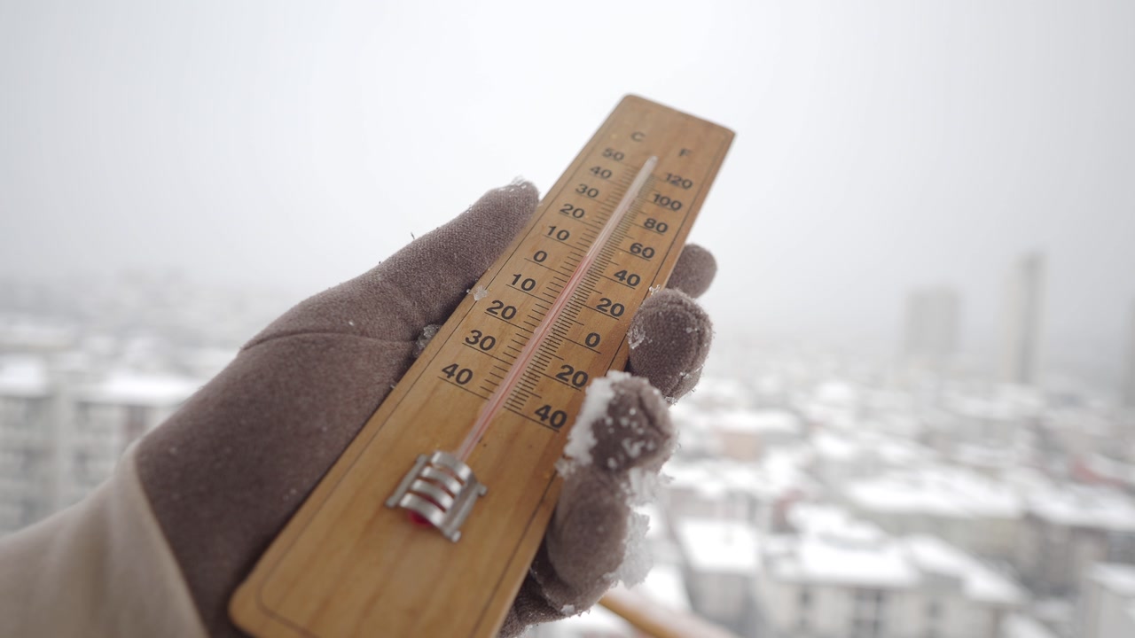 Gloved Hand Holding Thermometer Showing Cold Winter Temperature