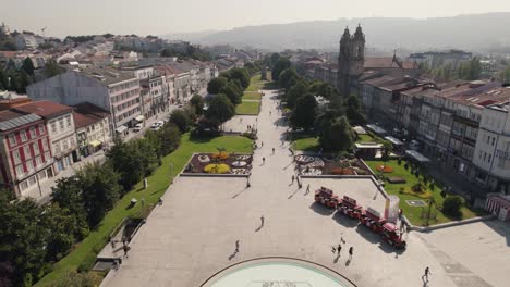 vista aérea delantera de una calle en el centro de la ciudad con macizos de flores y gente caminando