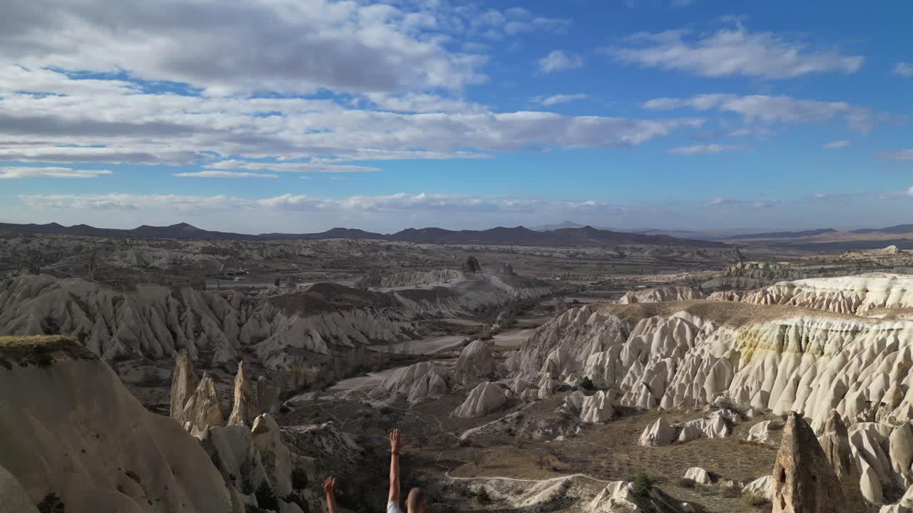 Coppia in piedi sulla scogliera che ammira i camini delle fate sul terreno roccioso a Goreme, Cappadocia, Turchia