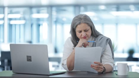 serious indian senior female manager reading business reports
