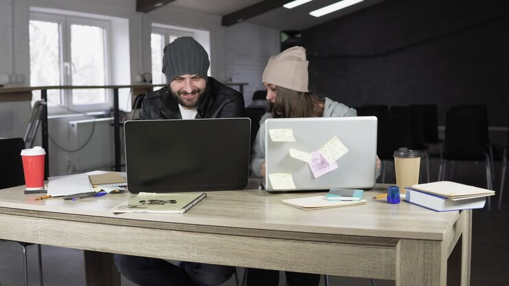 Young man and woman working in creative office. White and black laptops on the table. Modern design of the office. Shot in 4k