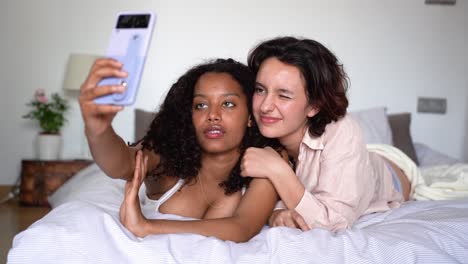 smiling young diverse girlfriends taking selfie with smartphone in daylight