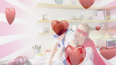 Animation-of-hearts-falling-over-caucasian-woman-and-her-son-playing-together-in-kitchen