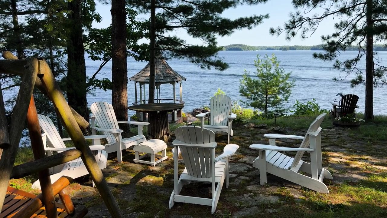 Una lenta panoramica rivela sedie Adirondack e un'altalena di legno accanto a un lago Muskoka.