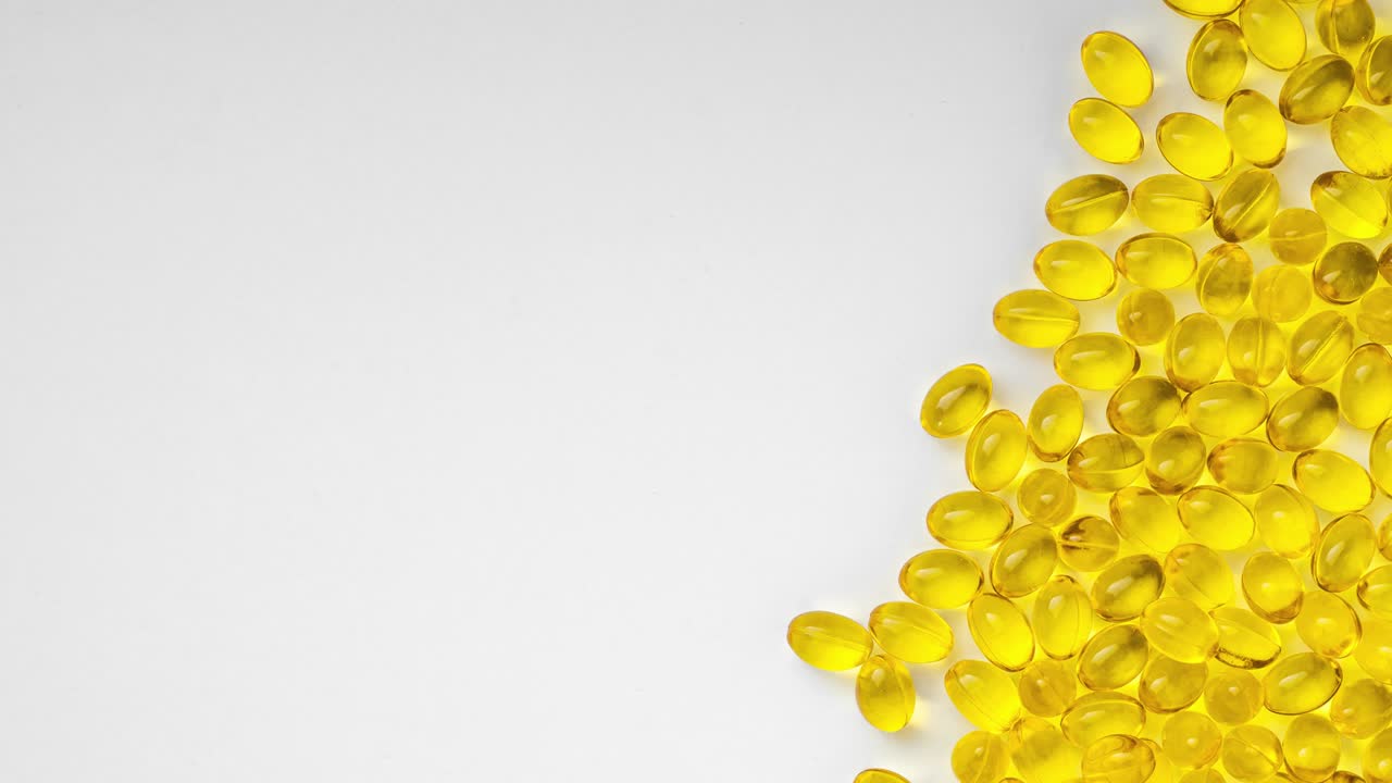 pastillas transparentes amarillas sobre un fondo blanco con un espacio de copia a la izquierda, video de movimiento de parada. pastillas con vitamina d3