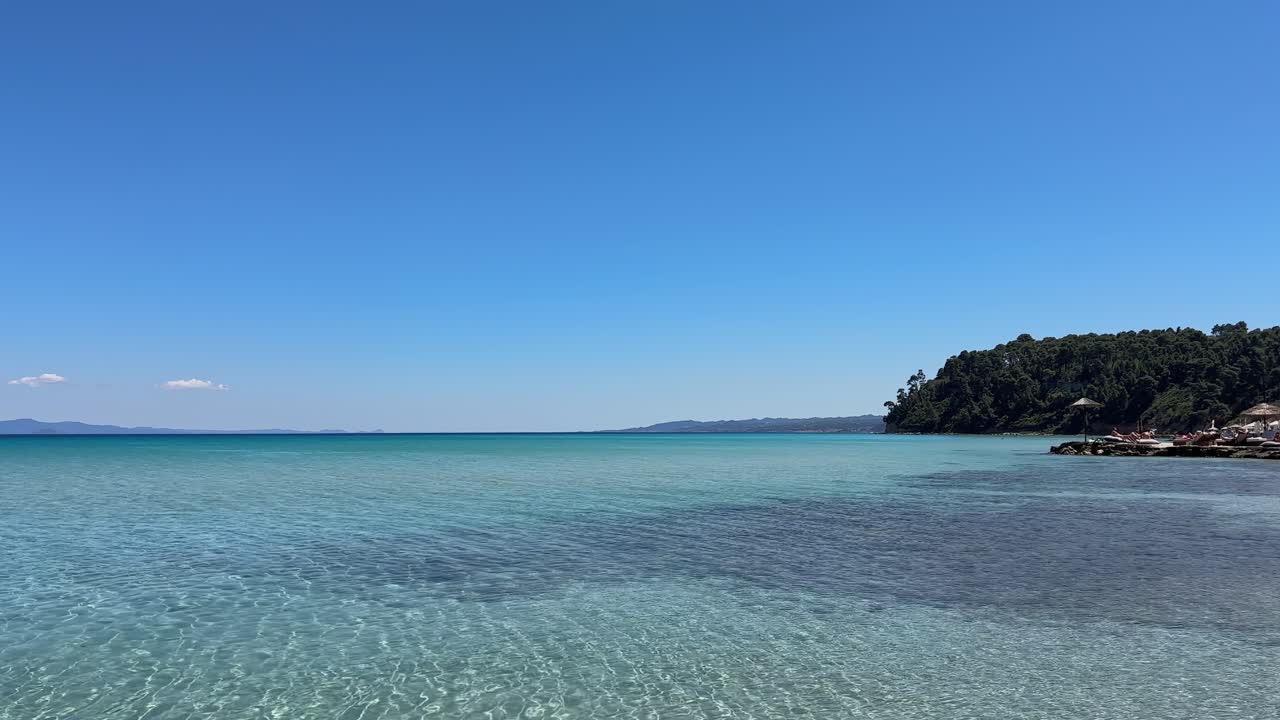 Stunning beach scene in Halkidiki, Greece, with elegant sunbeds facing the crystal-clear turquoise sea. A perfect summer escape in the heart of the Aegean.