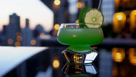 green cocktail with city sunset view