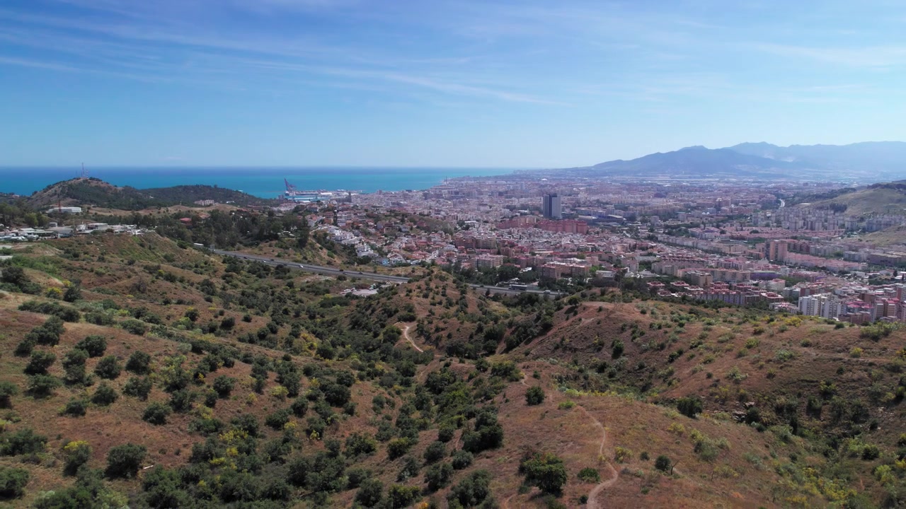 Vista aerea della città di Malaga e delle colline circostanti, che si muove lentamente all'indietro, Andalusia, Spagna.