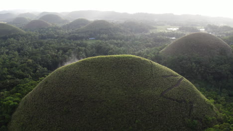 aerial shot trails climbing the interesting rock formations called the chocolate hills on bohol island in the philippines