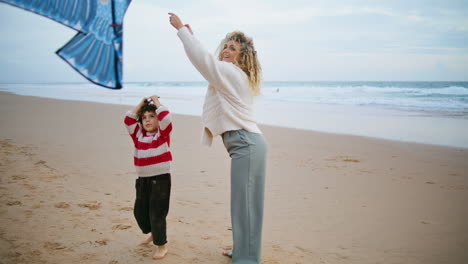 family playing kite together on windy seaside. happy mother spending weekend