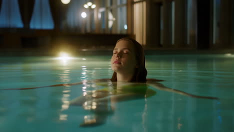 a woman relaxing in a dimly lit pool at night