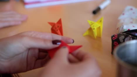 close up detail shot of a skilled white caucasian woman folding and origami, creating origami fox, oriental traditional japanese art on a wooden desktop