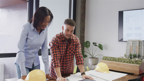 Portrait-of-happy-diverse-male-and-female-architects-standing-at-desk-with-blueprints,-slow-motion