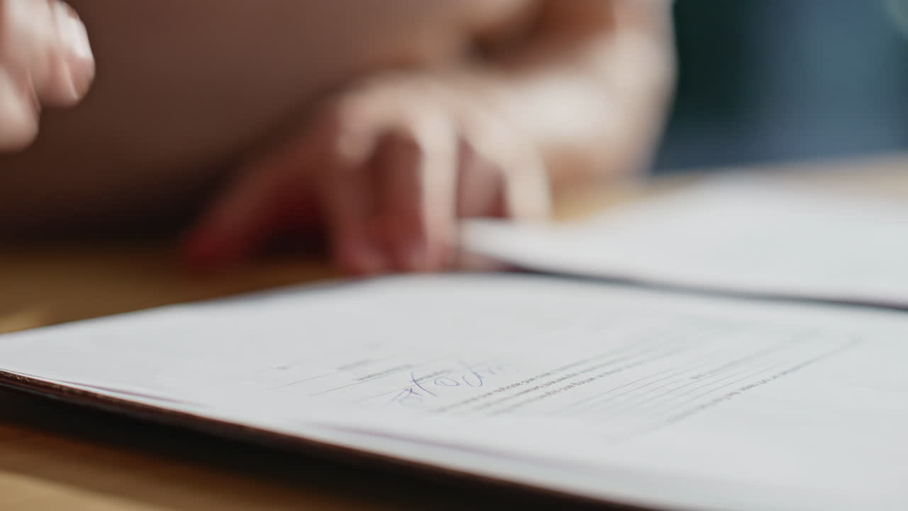 Hand reviewing business deal before writing signature at office table closeup