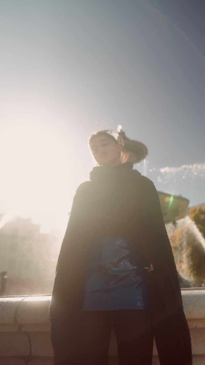 Woman in cape in front of fountain