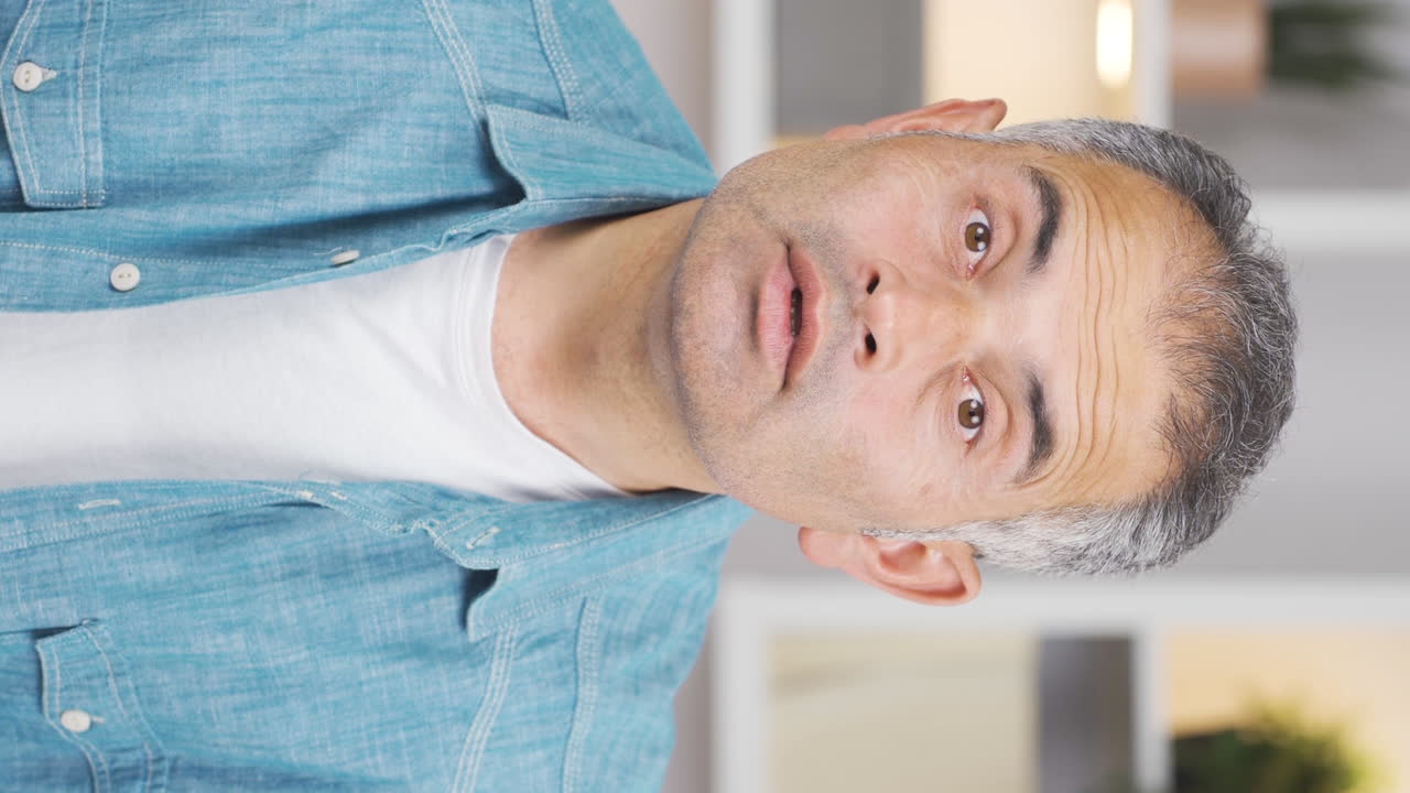 카메라를 놀라게 바라보는 남자의 수직 비디오.