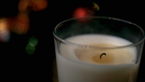 vela encendida frente a las luces de navidad