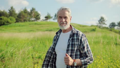 portrait of a senior man with beard in the park and looking at camera on a sunny day