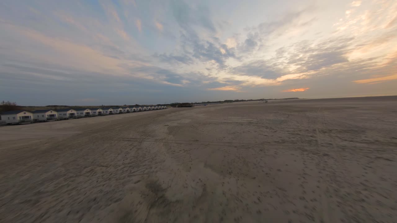 vuelo aéreo de drones a través de la playa vacía de vrouwenpolder al atardecer