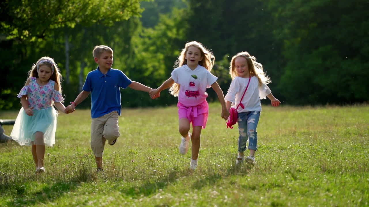 Happy children kid together run in the park holding hands. Kids walk outside. Four kids joyfully run. Little babies having fun in summer time.