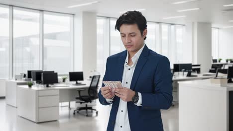 sad indian manager counting money in office