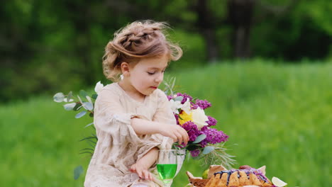 a funny smudgy girl sits on a table in the garden and eats a sweet cake with her hands traces of cho