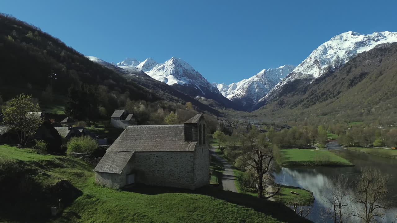 Aerial view on a church close to the banks of Lake Génos-Loudenvielle with snow capped mountains in the background, south western France.