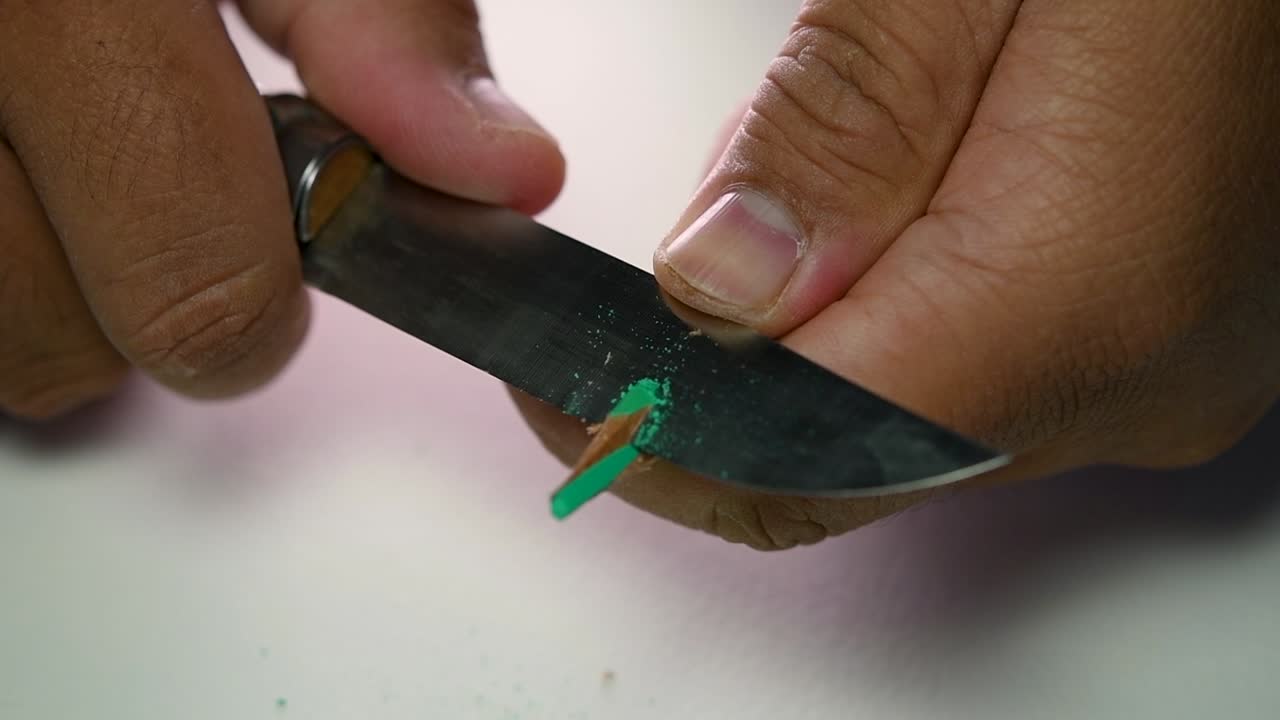 imágenes de manos afilando lentamente un lápiz y algunos lápices de colores con un cuchillo afilado