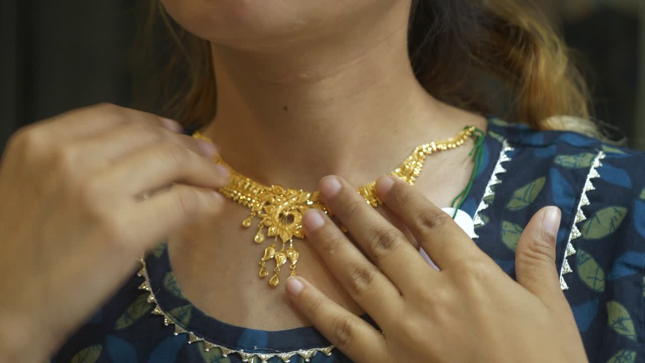 Young asian woman trying on a designer gold necklace, 18k HUID certified gold necklace, Closeup