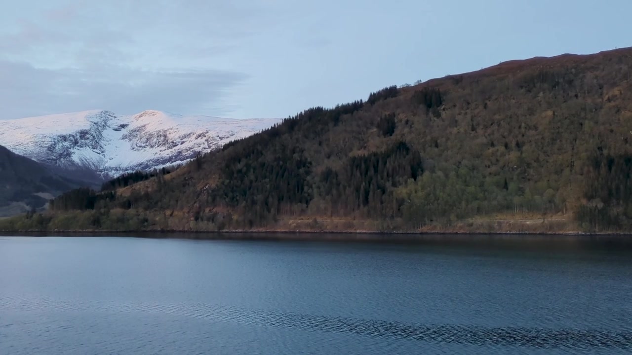 Montagne innevate e colline boscose lungo un fiordo norvegese